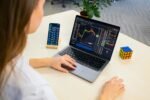 Woman using best free budgeting app and budget planner tools on laptop and smartphone, analyzing financial charts and monthly budget spreadsheets.