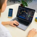 Woman using best free budgeting app and budget planner tools on laptop and smartphone, analyzing financial charts and monthly budget spreadsheets.