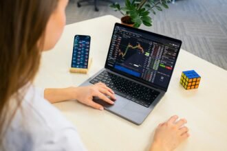 Woman using best free budgeting app and budget planner tools on laptop and smartphone, analyzing financial charts and monthly budget spreadsheets.
