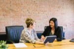Two women in a professional meeting discussing financial planning, representing Edward Jones Wealth Management services.