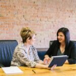 Two women in a professional meeting discussing financial planning, representing Edward Jones Wealth Management services.