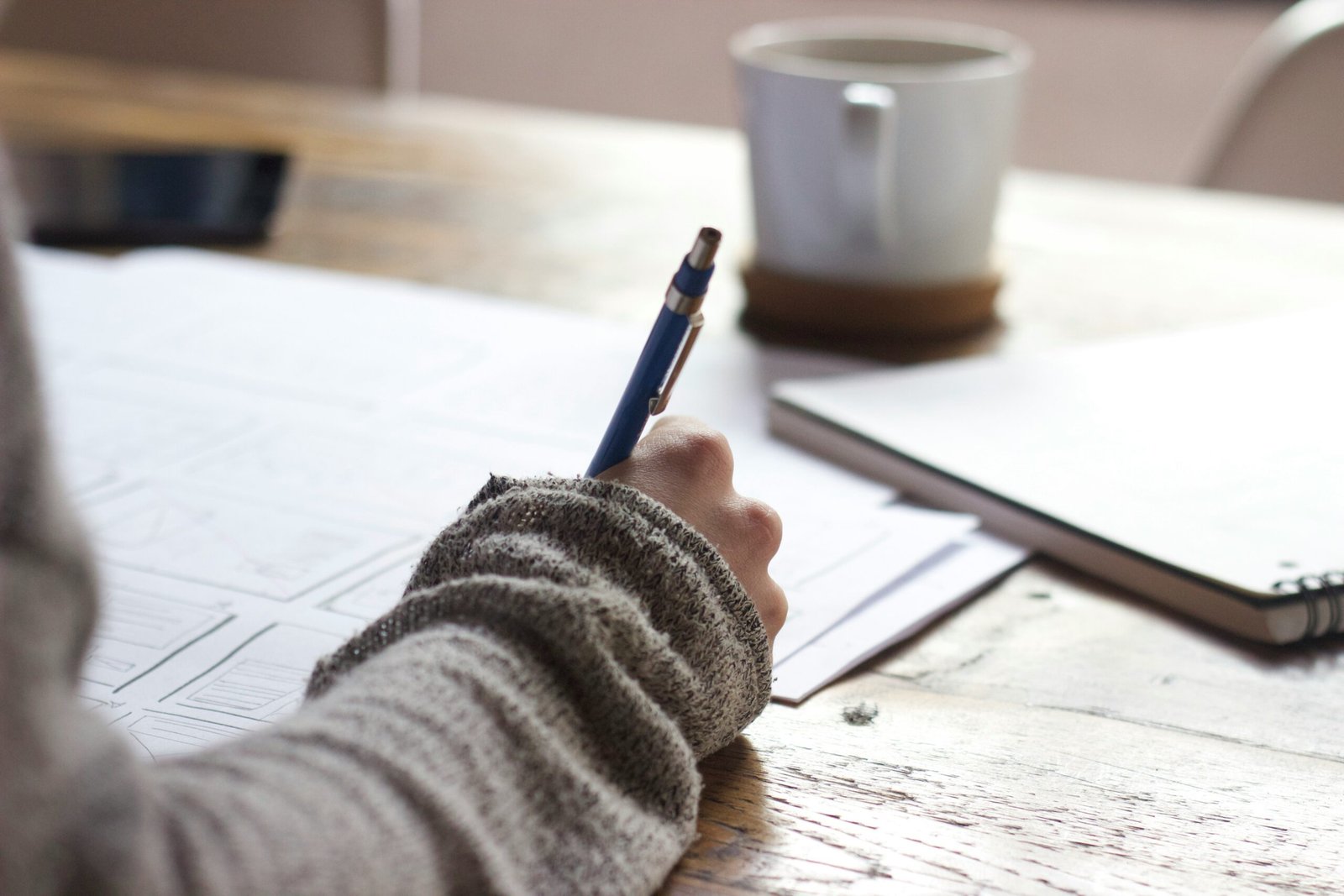 Person writing financial notes on a desk with a coffee cup and notebook, illustrating Personal Finance Advice, personal finance management, personal finance for beginners, and wealth management.