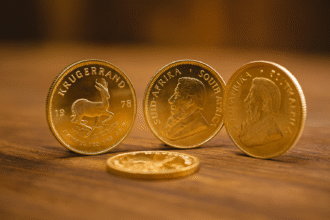 Gold Krugerrand coins displayed on a wooden table with blurred background